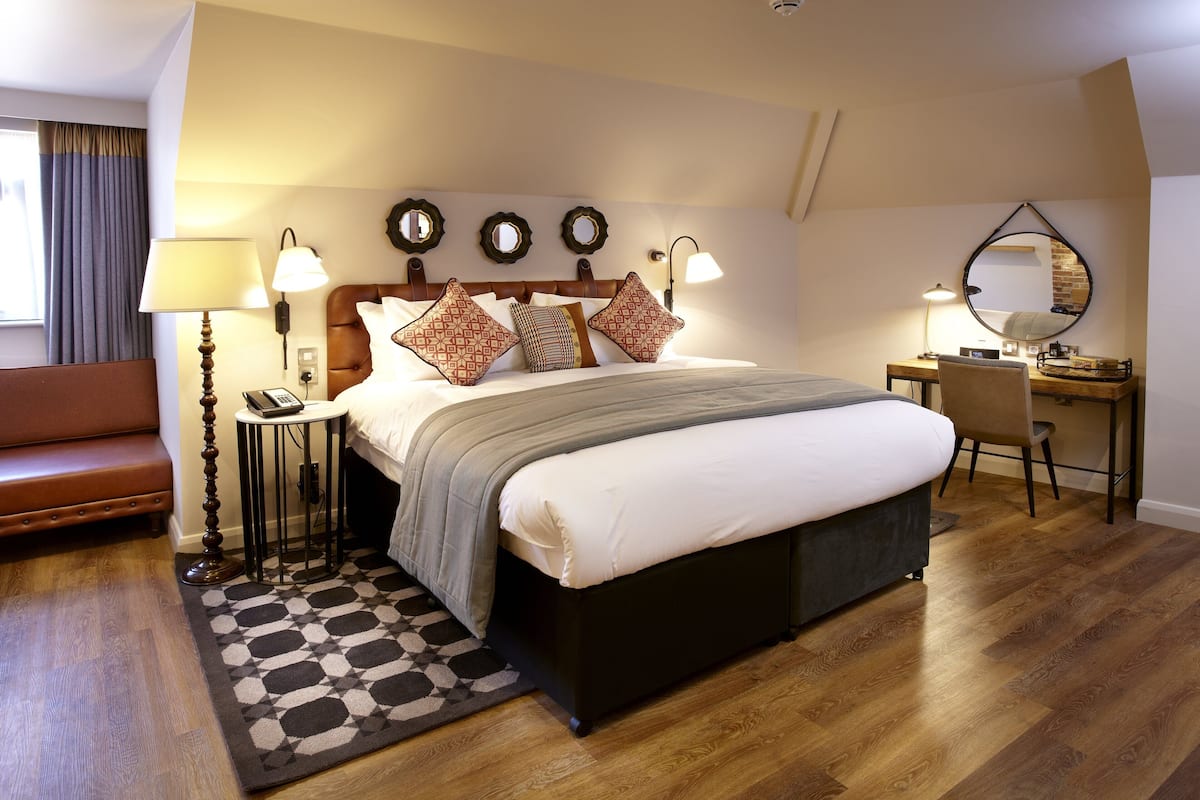 A modern hotel room with a large bed, bedside lamps, a desk, and a chair.