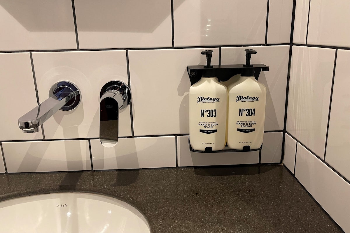A bathroom with a white sink, two hand and body wash bottles labeled 'Biology', and a modern faucet.