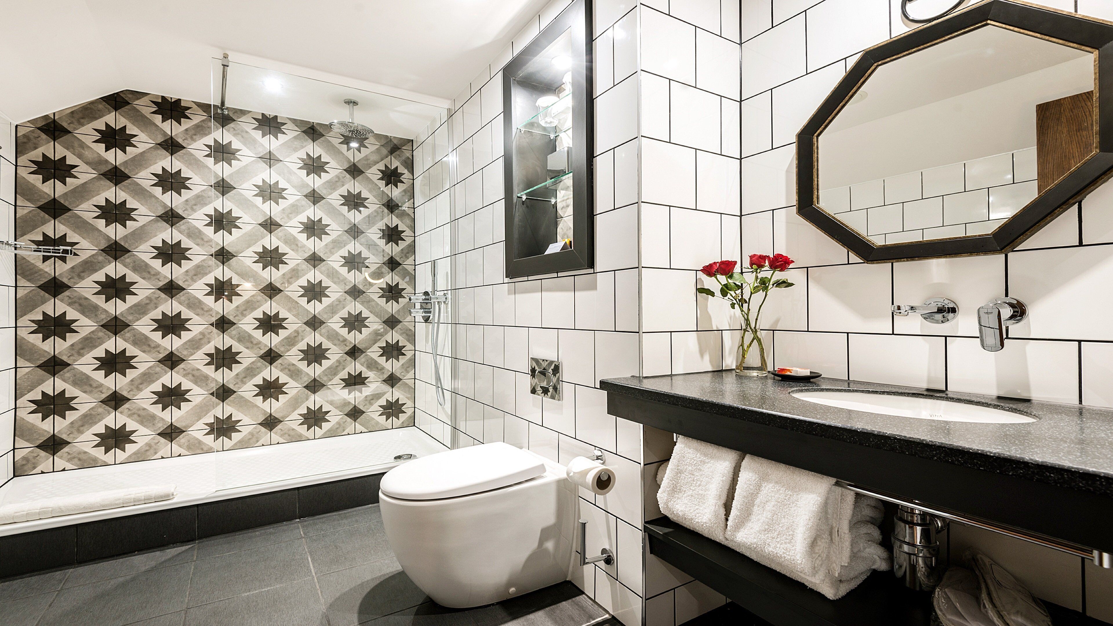 A bathroom with a shower, toilet, sink, and two mirrors.