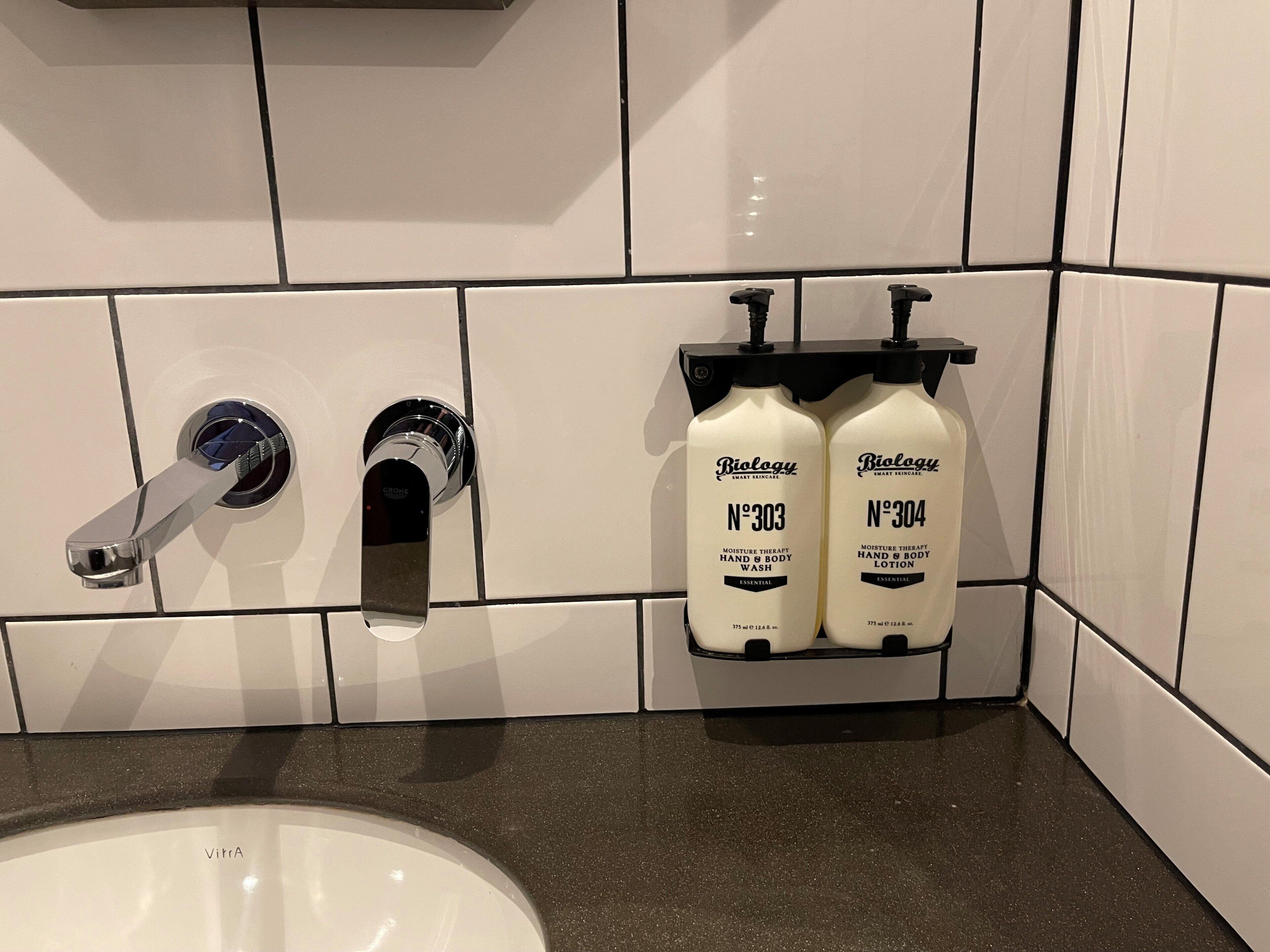 A bathroom with a white sink, two hand and body wash bottles labeled 'Biology', and a modern faucet.