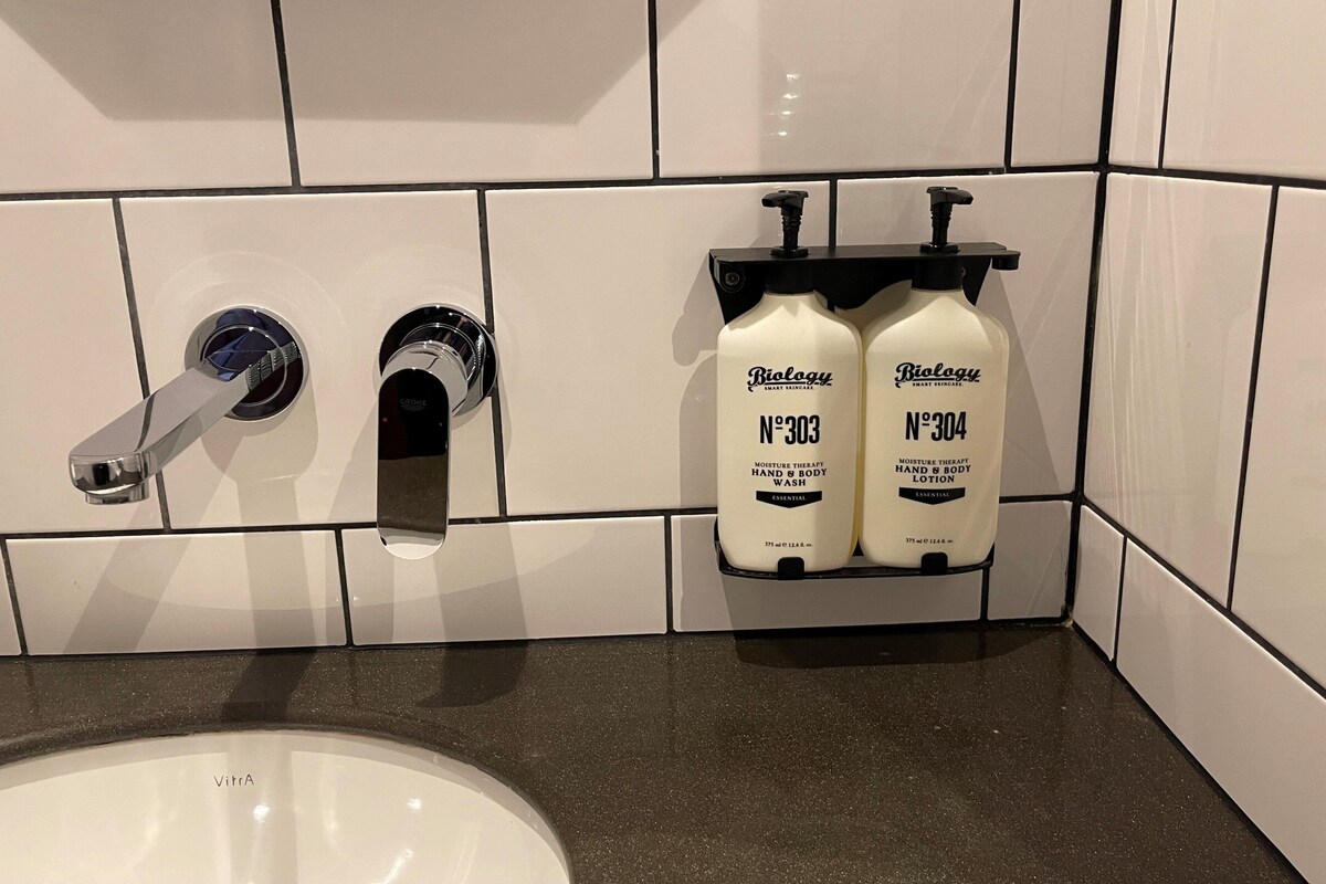 A bathroom with a white sink, two hand and body wash bottles labeled 'Biology', and a modern faucet.