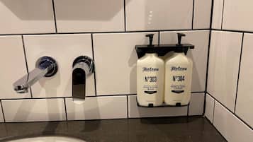 A bathroom with a white sink, two hand and body wash bottles labeled 'Biology', and a modern faucet.