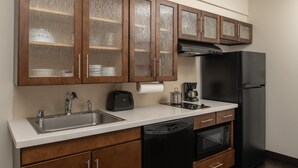 Una cocina con armarios de madera, lavavajillas, refrigerador y cafetera.