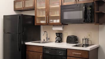Una cocina con un refrigerador negro, un microondas, una cafetera y un tostador.