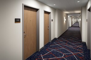 A hotel hallway with wooden doors, numbered room signs, and a patterned carpet. - Candlewood Suites Vancouver-Camas by IHG (Vancouver)