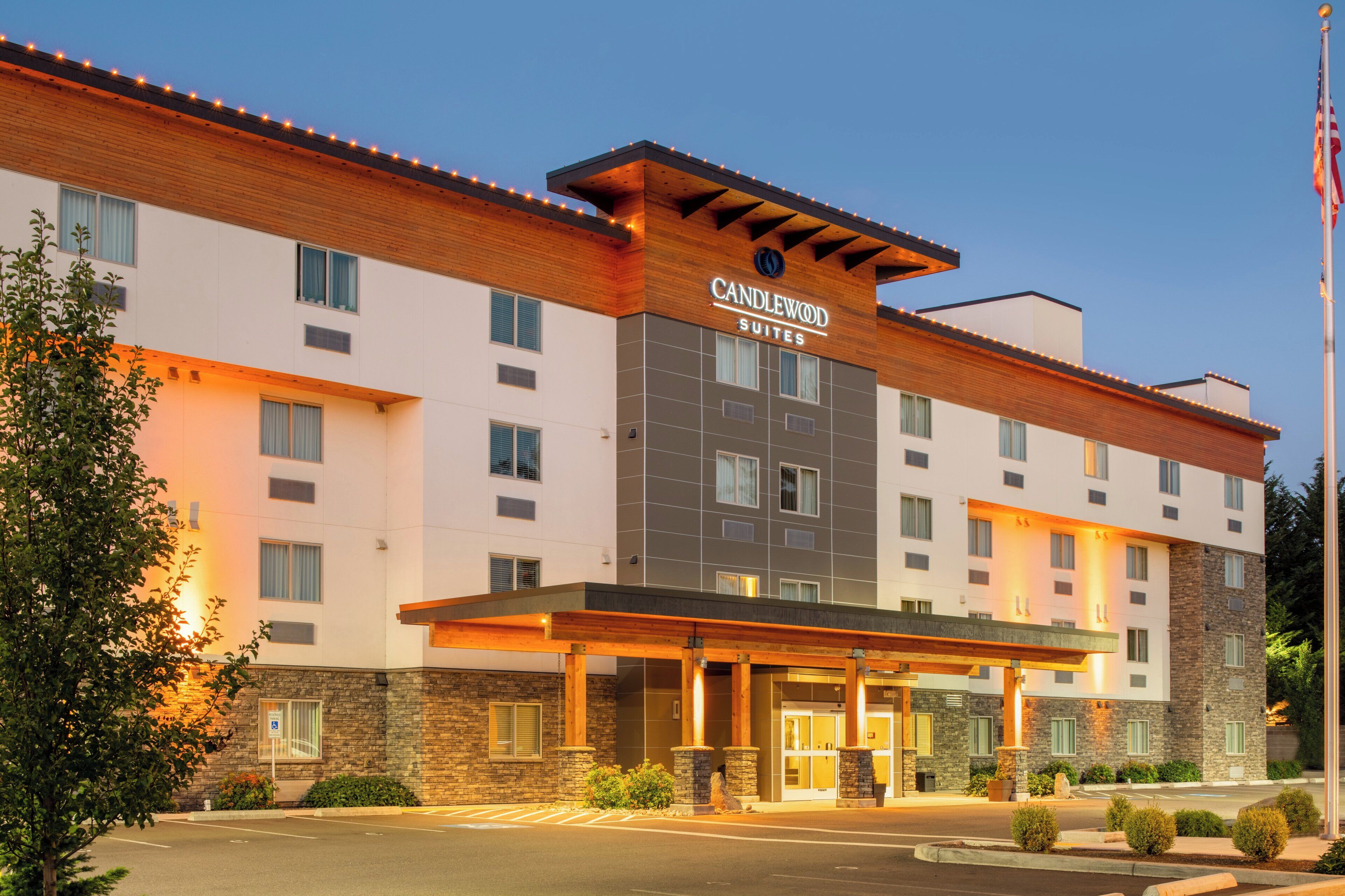 Un hotel de diseño moderno, con una entrada destacada que incluye un corredor cubierto y un letrero que dice 'Candlewood Suites'.