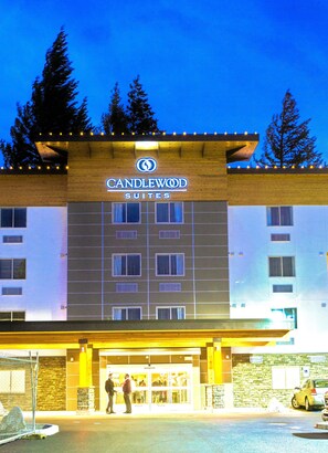 Ein Hotel mit einem Schild, auf dem "CANDLEWOOD SUITES" steht, und einem Eingangsbereich, vor dem Personen stehen.