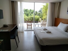 Une chambre d’hôtel avec un lit, un bureau et une vue sur un jardin par la fenêtre.