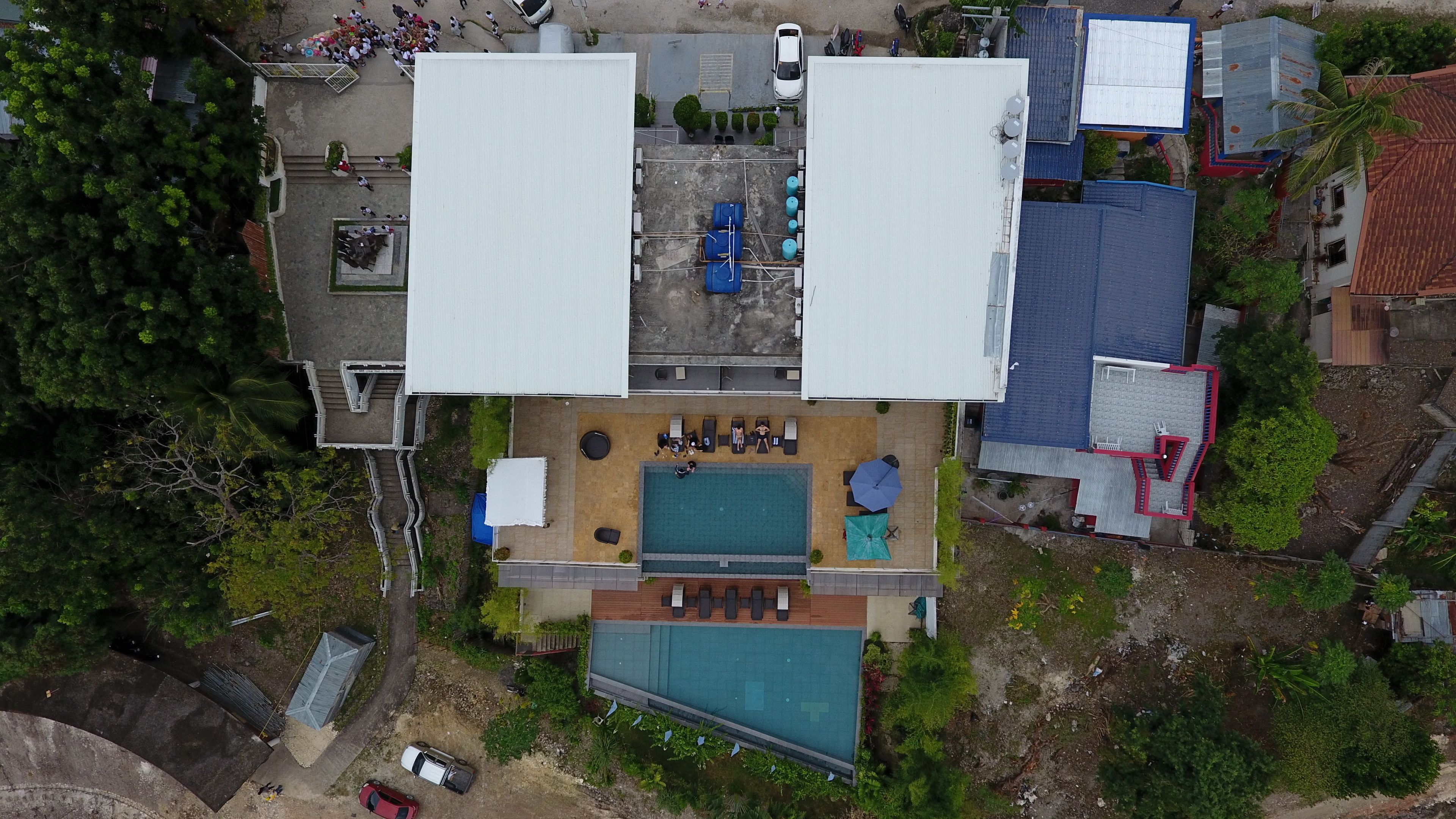 Vista aérea de una propiedad residencial con piscina, zona de estar al aire libre y un porche cubierto.