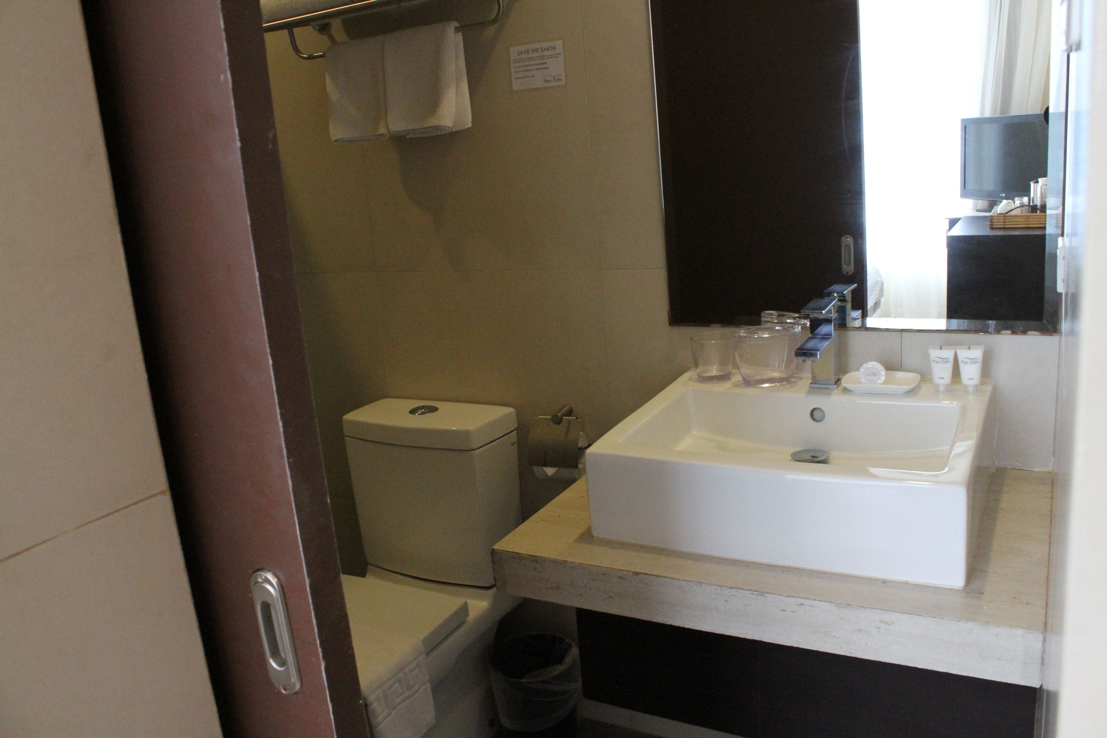 Un bagno con un lavandino bianco, un water, un cestino e un asciugamano su un porta-asciugamani.