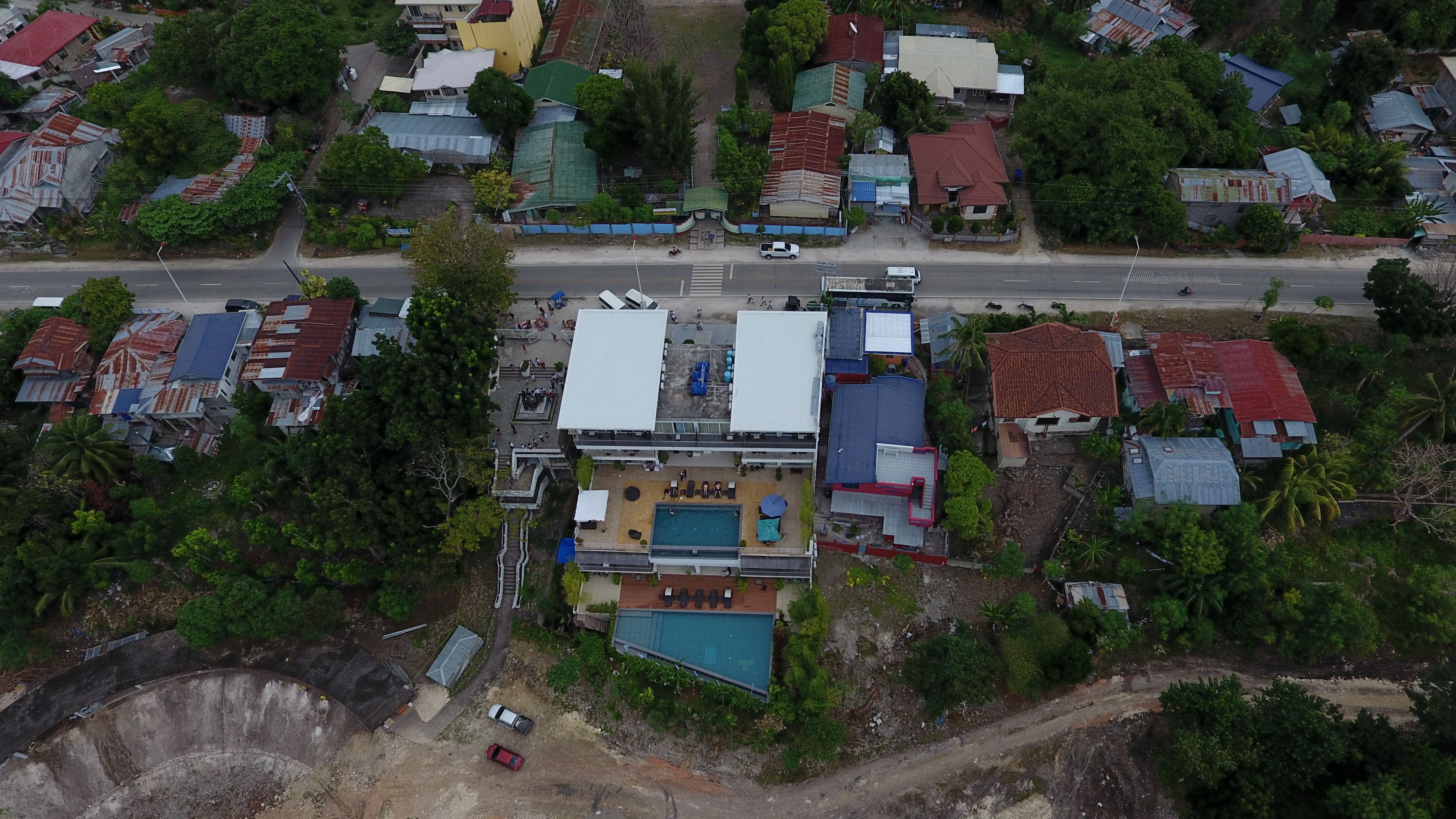 Vue aérienne d’un quartier résidentiel avec des maisons, une piscine et une route.
