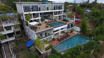 Un hôtel à plusieurs étages doté d’une piscine sur le toit, d’un espace extérieur aménagé et d’un escalier menant aux étages supérieurs.