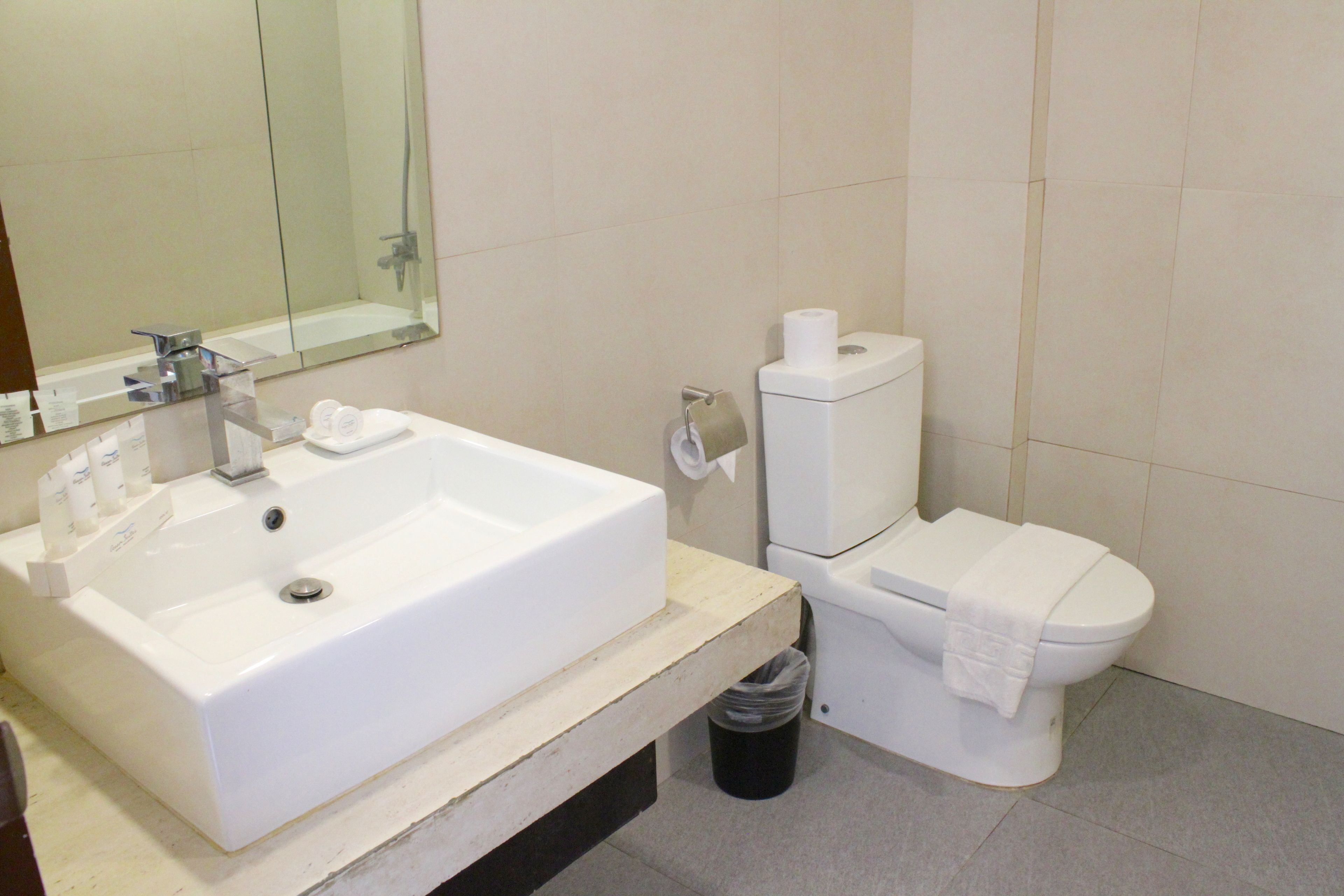 A bathroom with a white sink, mirror, and toilet.