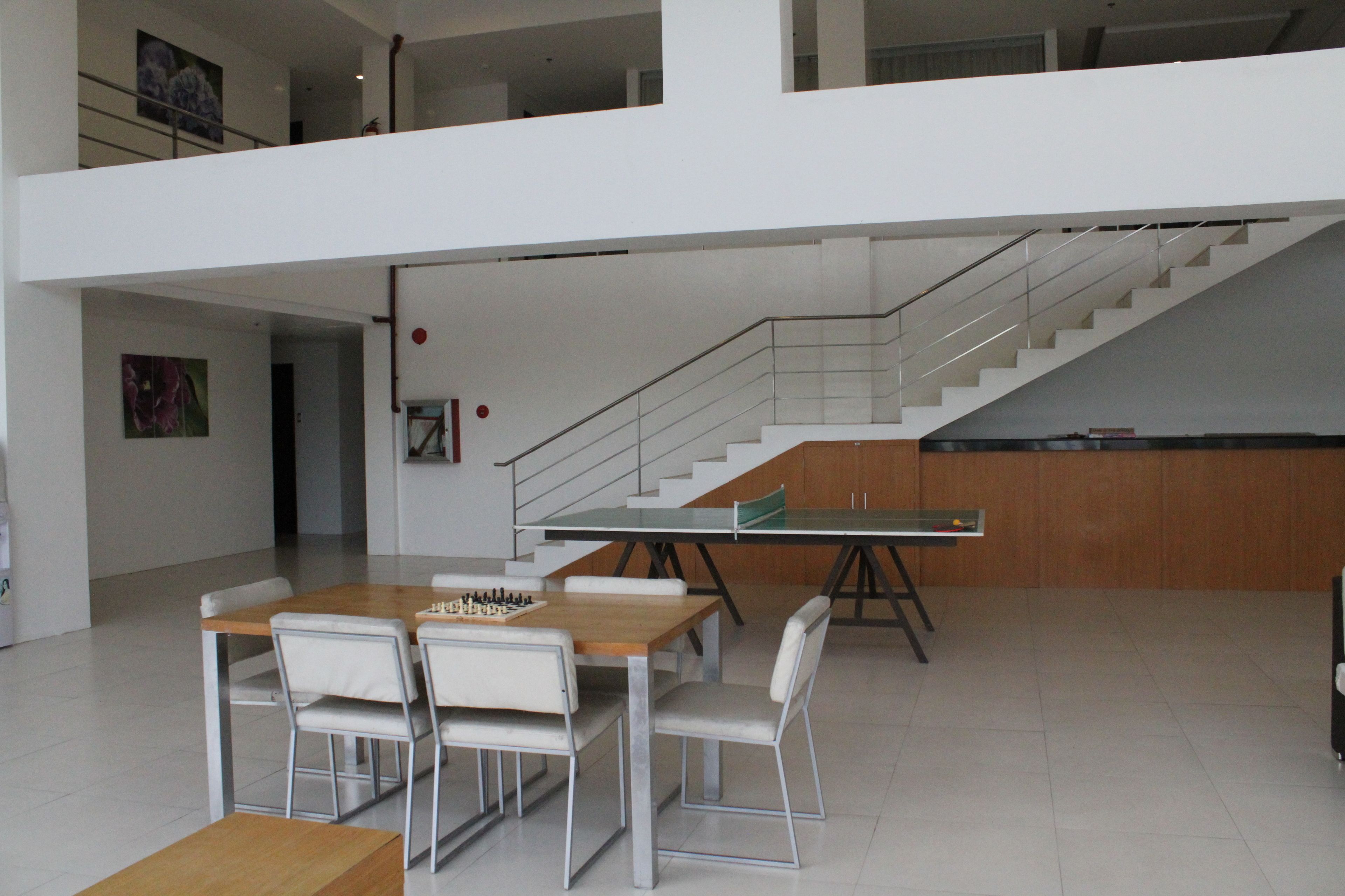A spacious, modern interior with a dining area featuring a wooden table and chairs, a staircase, and a view of the upper floor.