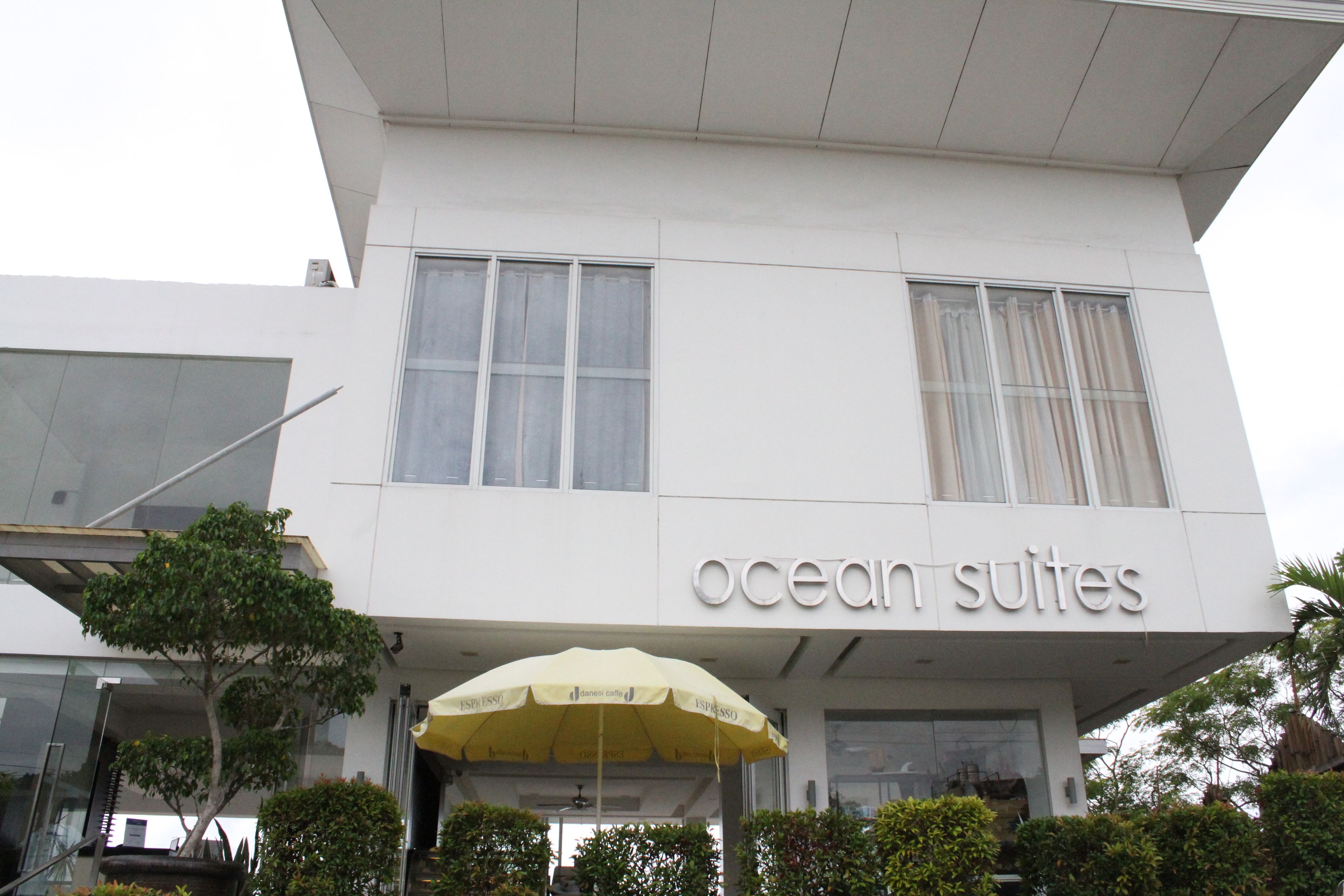 Un edificio con un letrero que dice "ocean suites" y un paraguas amarillo al frente.