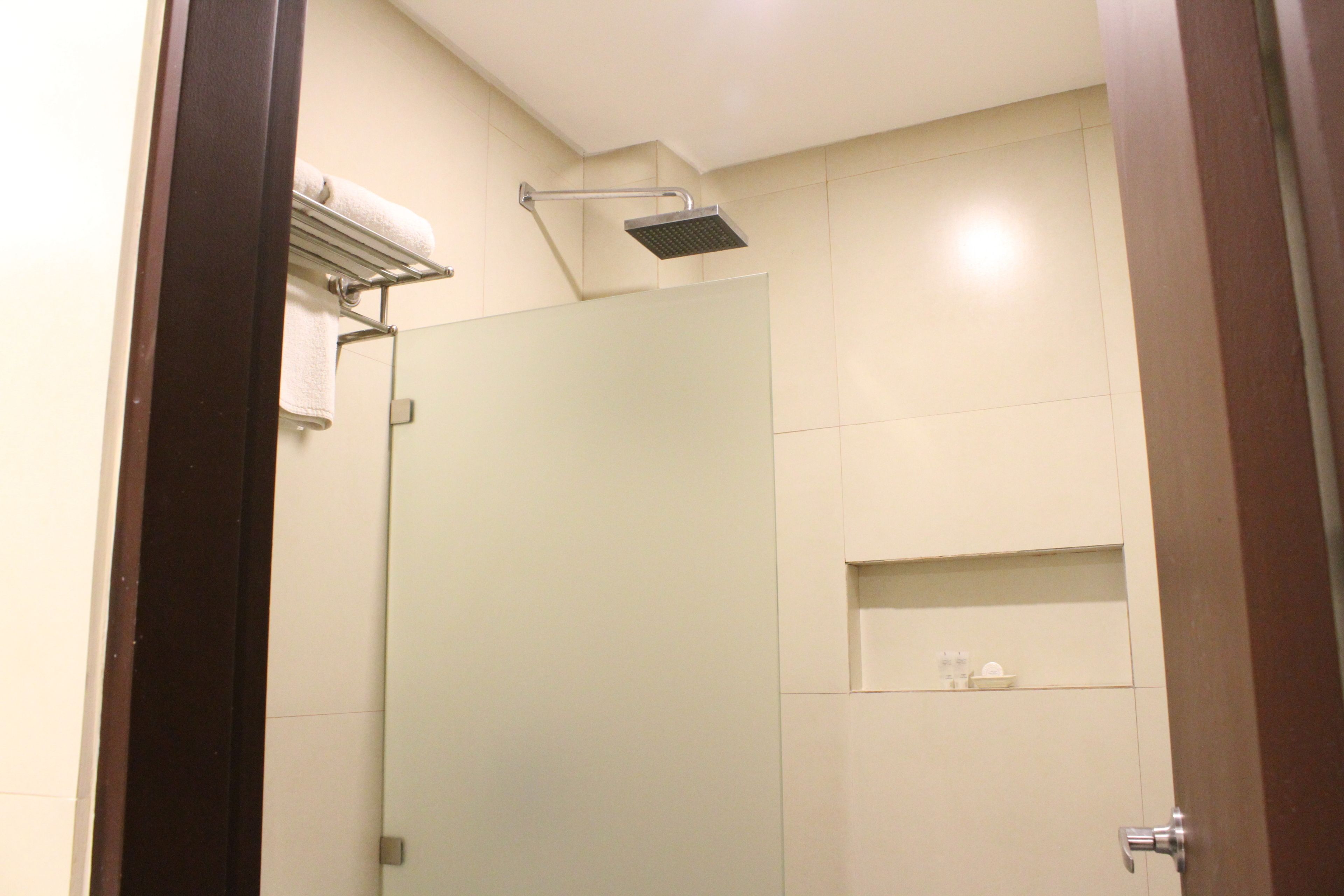 Un baño moderno con cabina de ducha de vidrio, un perchero y un estante pequeño con artículos de aseo.