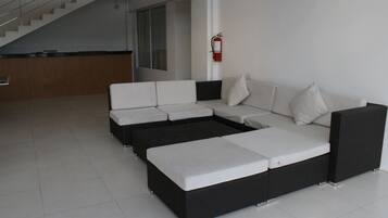 Een moderne woonkamer met een modulaire bank, een zwart-wit salontafel en een trap naar een hoger niveau.