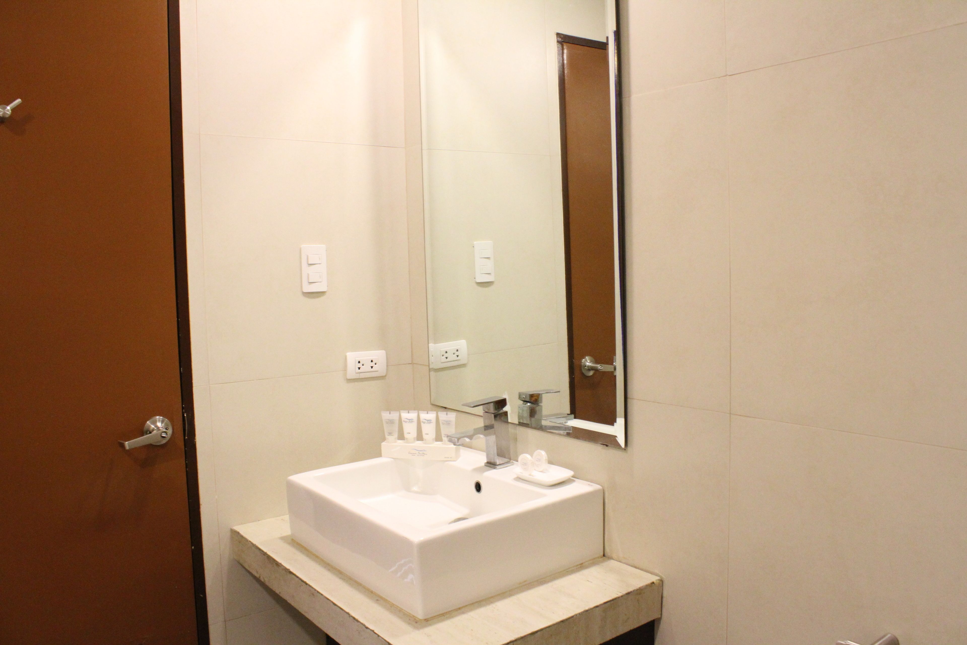 A bathroom with a white sink, a mirror, and a door.