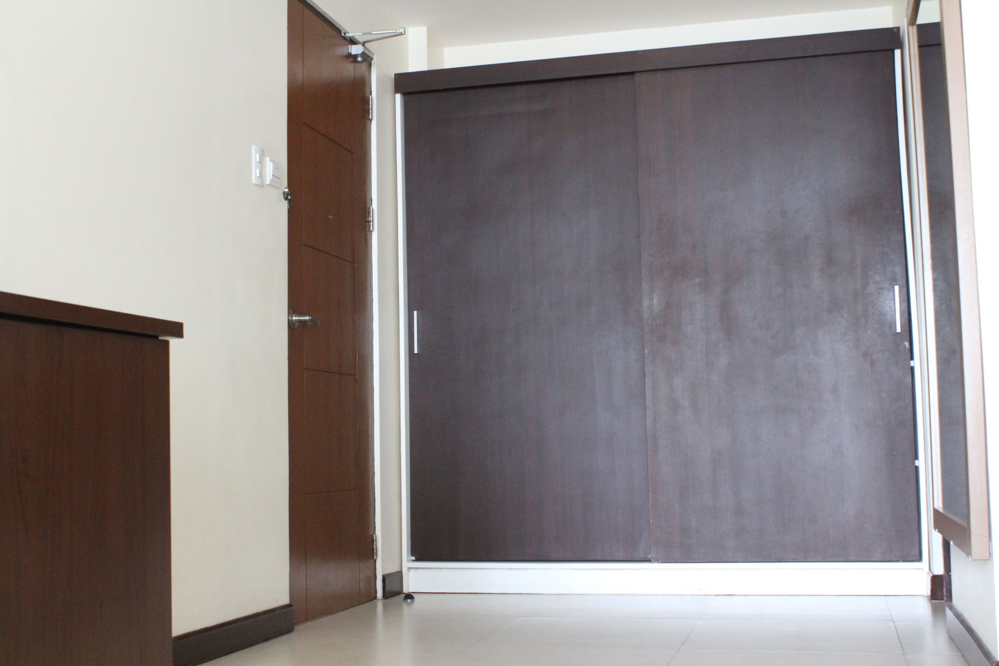Puerta corrediza cerrada con acabado oscuro, pared blanca y suelo de madera.