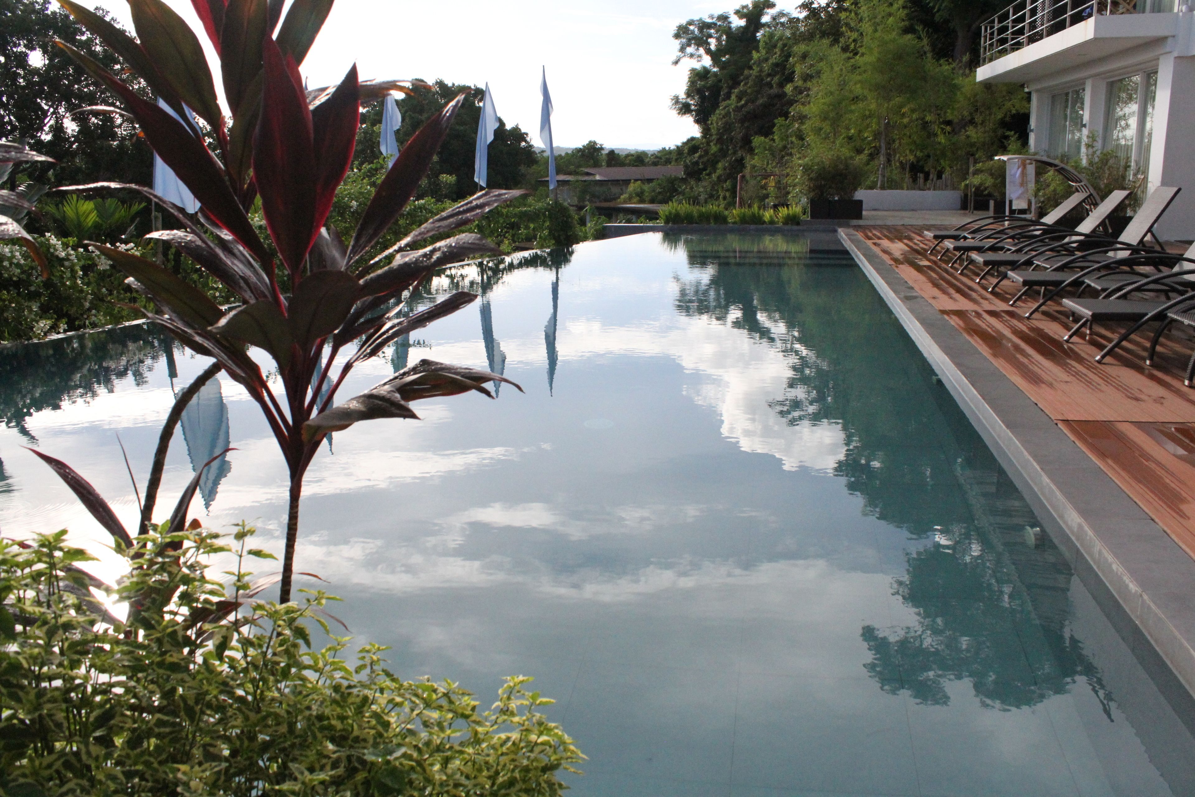 A swimming pool with lounge chairs and a reflection of the sky.