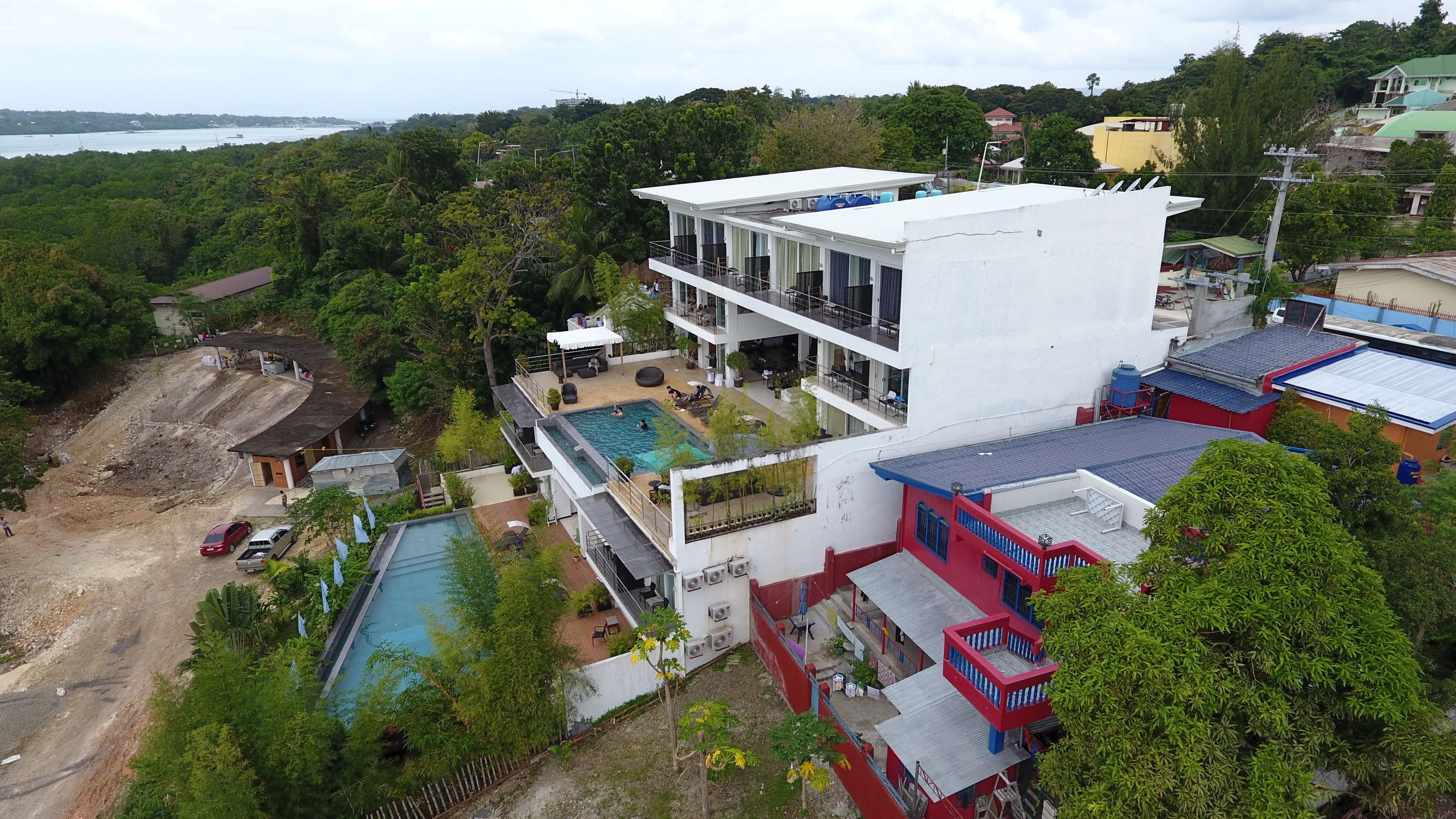 A multi-story building with a rooftop pool and a large outdoor swimming pool.