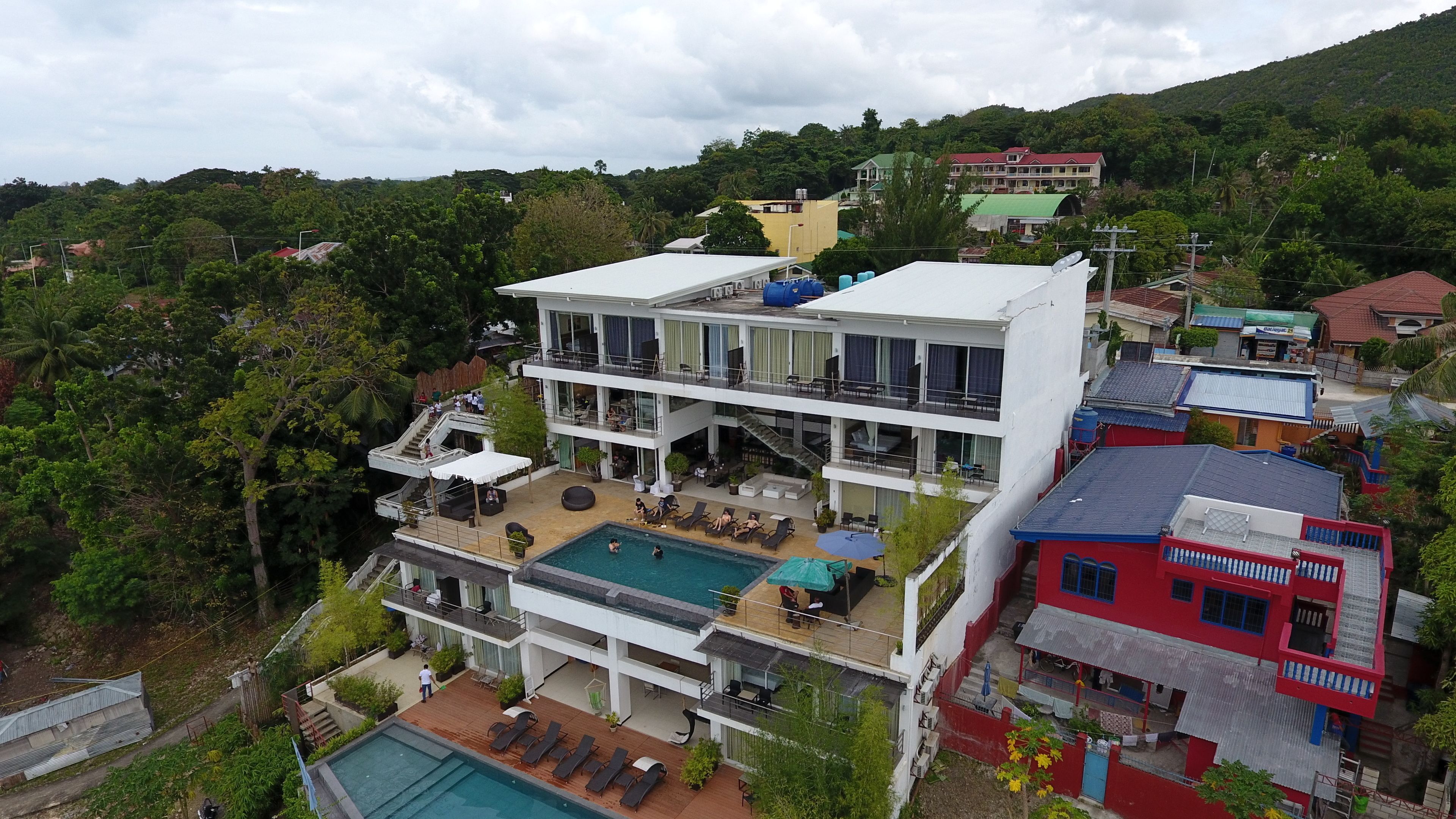 A multi-story hotel with a pool, outdoor seating, and a view of the surrounding greenery.