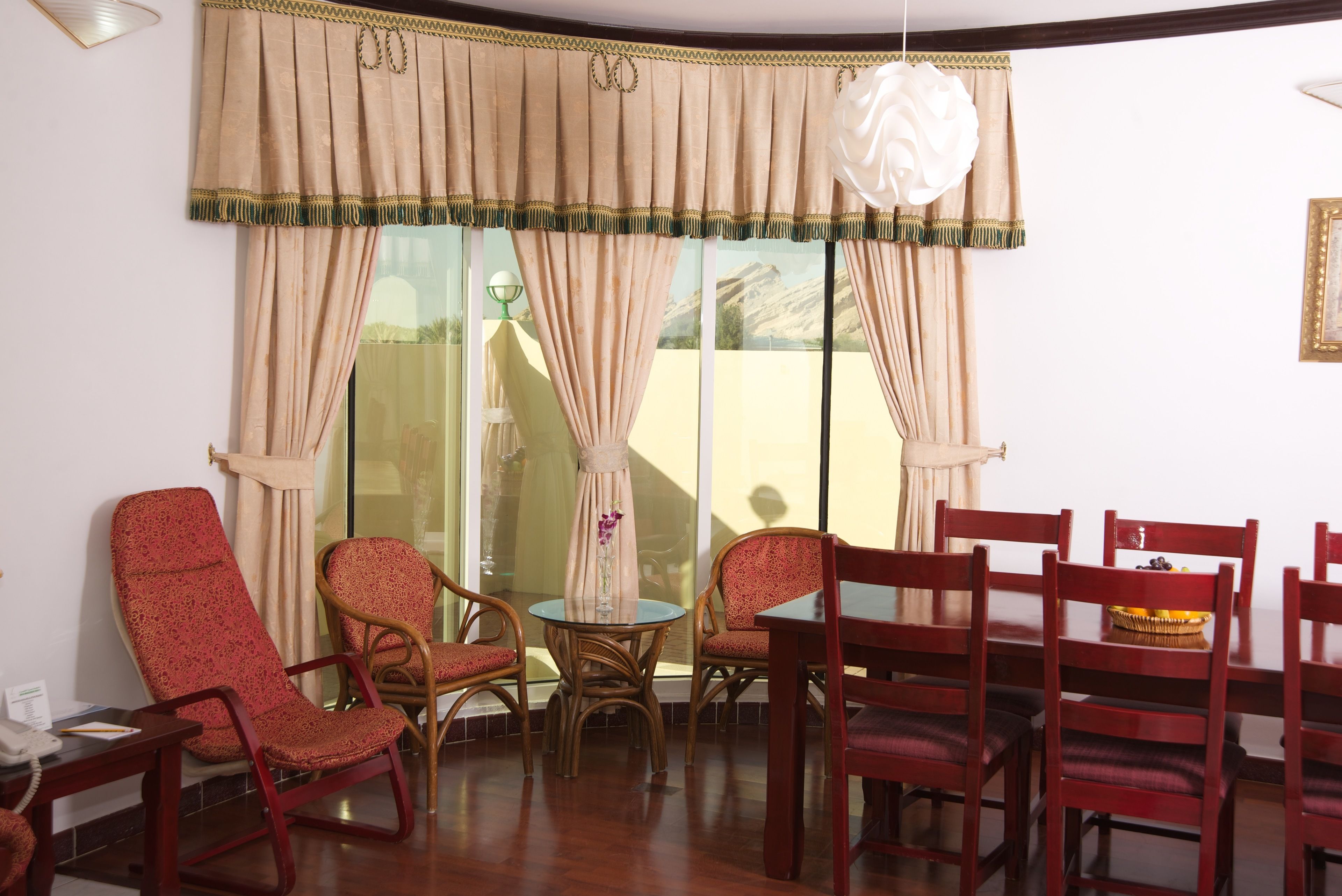 A room with a dining table, chairs, and a window with curtains.