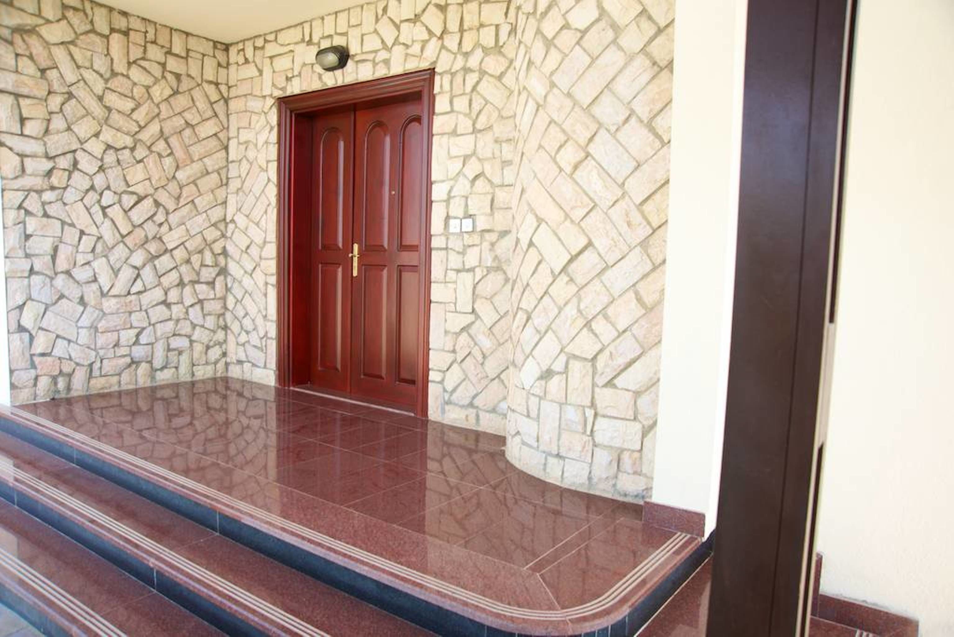 Un mur de pierre avec une porte en bois et un escalier menant à un niveau supérieur.