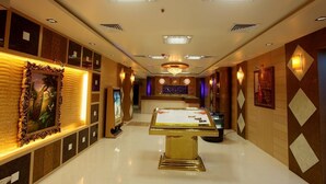 A hotel lobby with a central reception desk, framed artwork on the walls, and a chandelier. - Grand Elite hotel (Hyderabad)