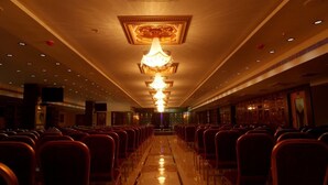A hotel lobby with rows of red chairs, a central chandelier, and a polished floor. - Grand Elite hotel (Hyderabad)