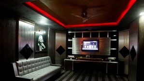 A modern living room with a sofa, a flat-screen TV, and a ceiling fan. - Grand Elite hotel (Hyderabad)
