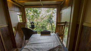Simple, functional space with a small bed, wooden chair, and table.