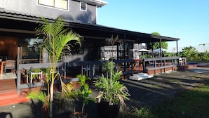 A modern building with a covered outdoor seating area and potted plants. - Travellers Point Hotel (Apia)