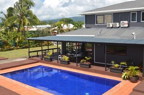 Una casa moderna con piscina, mobiliario exterior y unidades de aire acondicionado.