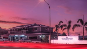 A hotel with a two-story structure, a signboard, and a street with light trails. - Travellers Point Hotel (Apia)