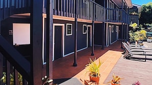 A modern building with a covered outdoor area featuring multiple balconies, potted plants, and outdoor seating. - Travellers Point Hotel (Apia)