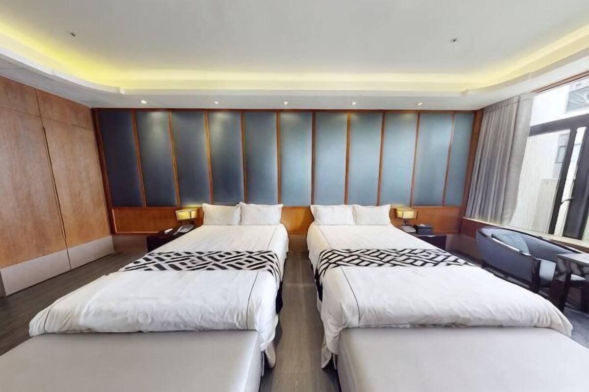 Una habitación de hotel con dos camas, un ventanal grande y un diseño moderno.
