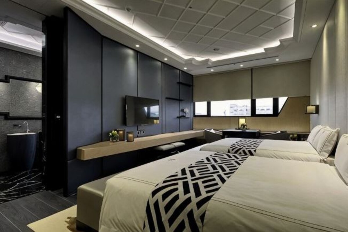 Una habitación de hotel moderna con una cama grande, televisión, escritorio y baño.