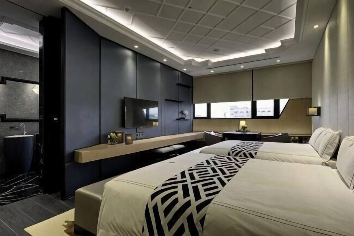 Una habitación de hotel moderna con una cama grande, televisión, escritorio y baño.