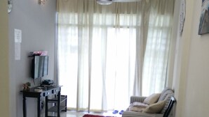 A living room with a blue playpen, a sofa, a television, and a ceiling fan. - H&A Guest House (Malacca City)