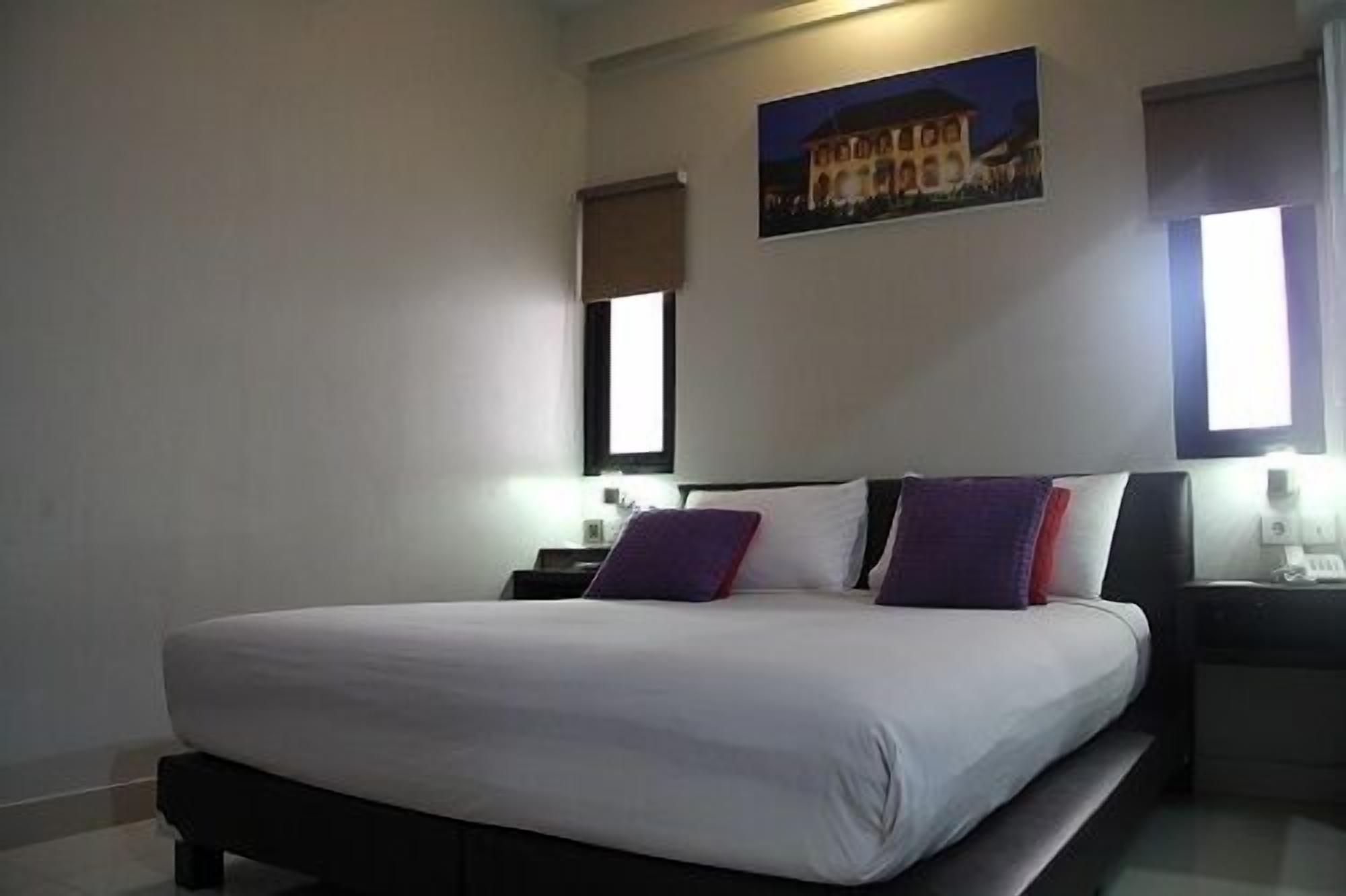 A bedroom with a large bed, two bedside tables, and a painting on the wall.