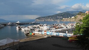 A marina with boats docked, a pier extending into the water, and a mountainous backdrop. - Surriento Suites (Sorrento)