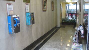 A hallway with public phones, a bulletin board, and a magazine rack.