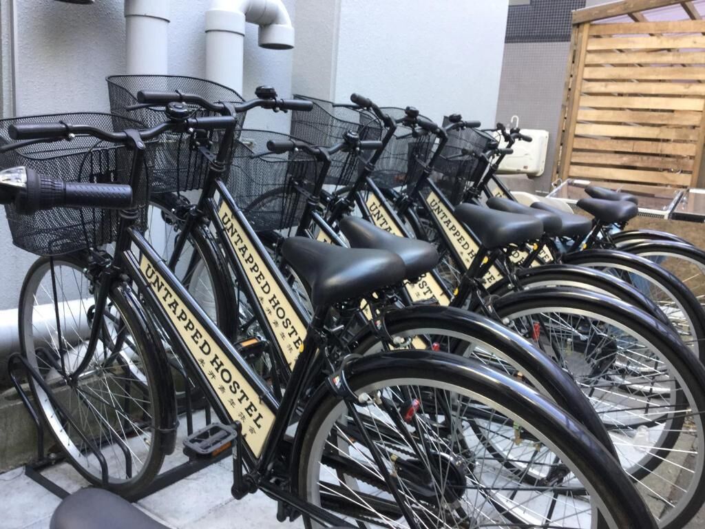 En række cykler med skilte der angiver "UNTAPPED HOSTEL", der viser en cykeldelingsservice.