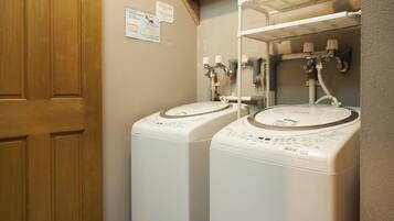 A laundry room with two front-loading washing machines and a wooden door.