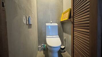 Un bagno piccolo e stretto, con il water, un asciugamani ad aria e un cestino.