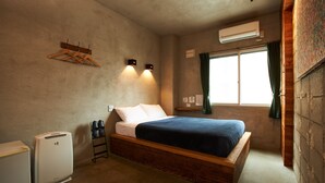 A bedroom with a wooden bed, a small bedside table, a wall-mounted heater, and a window with curtains. - Untapped Hostel (Sapporo)