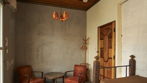 A room with a wooden door, a round table, two armchairs, and a ceiling light fixture. - Untapped Hostel (Sapporo)
