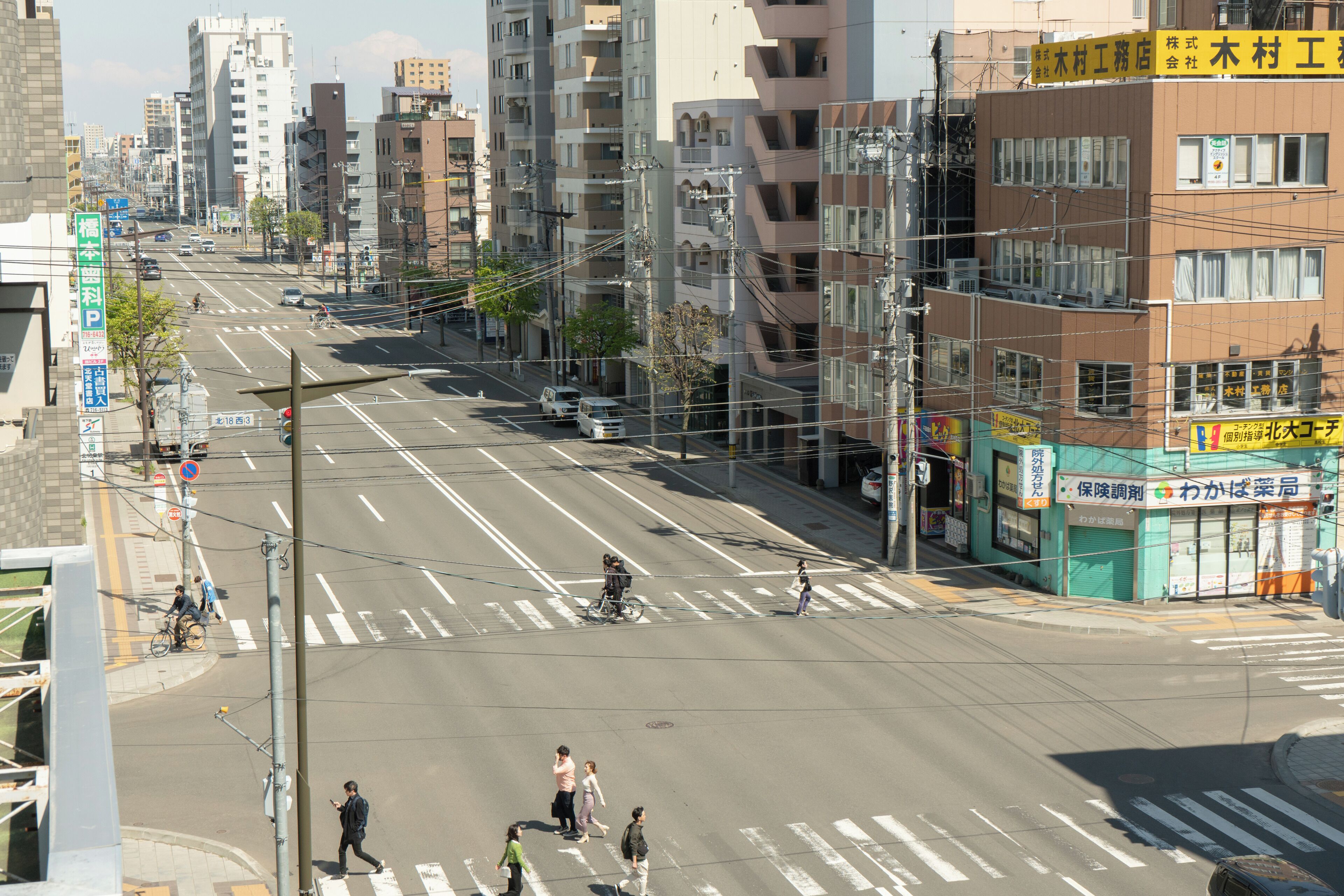 Straßenansicht mit Gebäuden, Fußgängerüberwegen und Fahrzeugen.