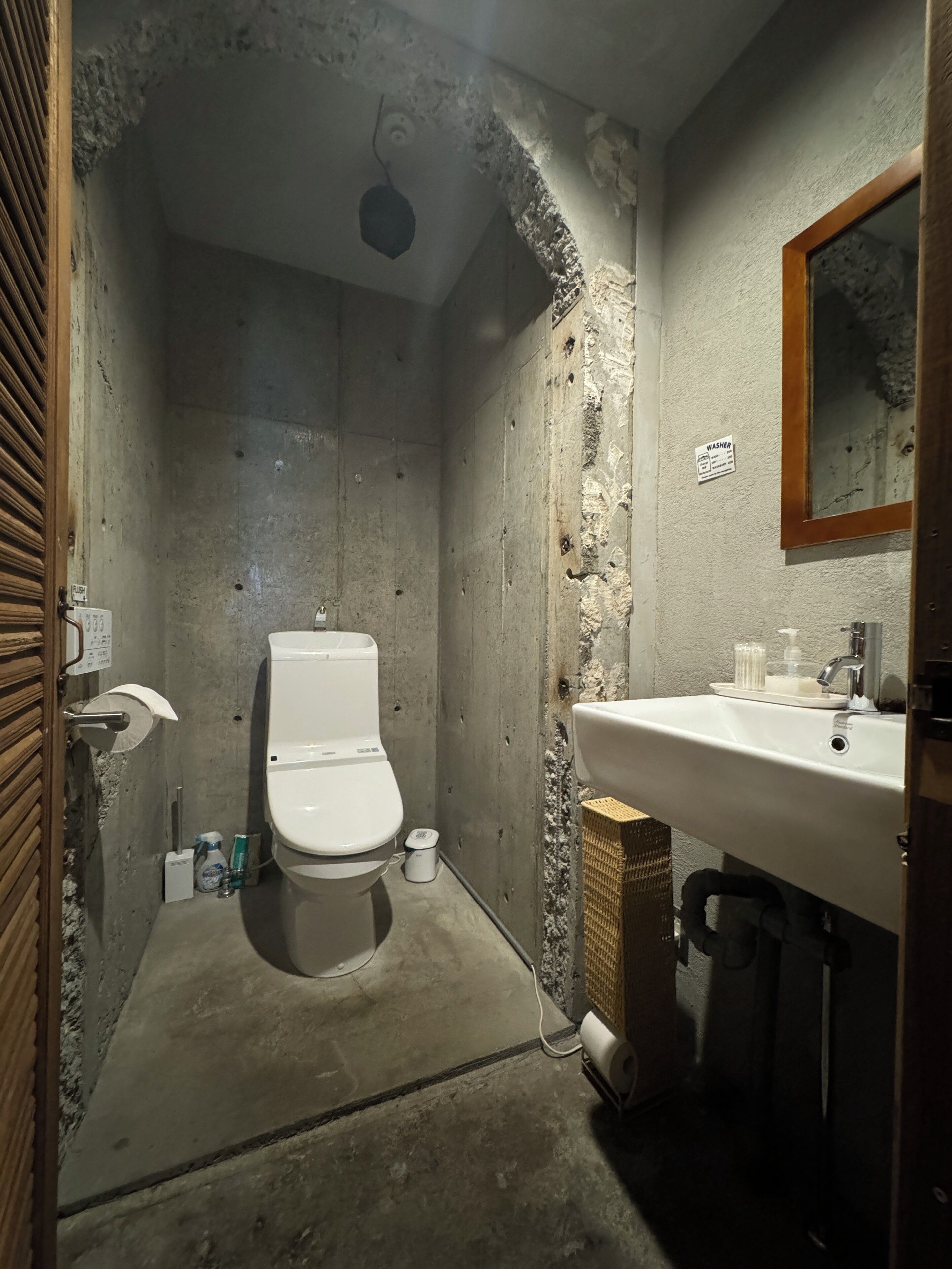 A small, narrow bathroom with a toilet, sink, and shower area.